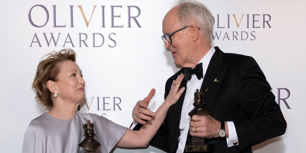 Lesley Manville and John Lithgow looking at each other, each holding an Olivier Awards trophy